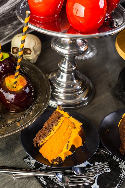 Table with colored candy apples and cake for Halloween party.