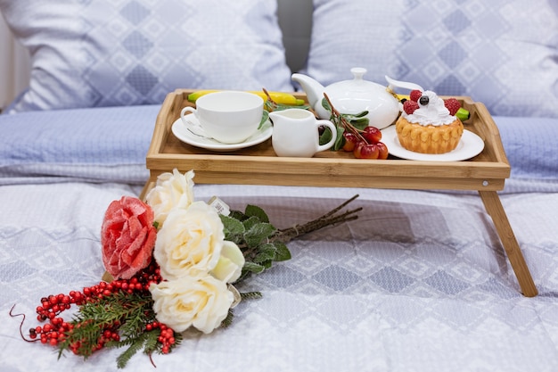 Table with a cup and a flower on the bed, coffee in bed in the
morning