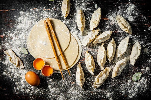 A table with flour and eggs with dumplings on it