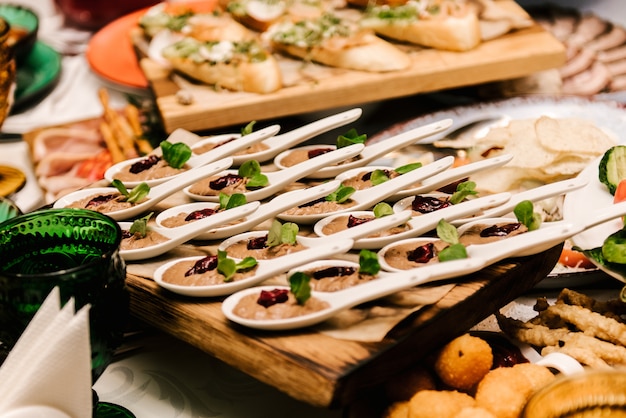 Table with food for the holiday. Snacks in the form of spoons with sauces and seasonings, selective focus