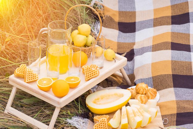 Photo a table with fruits and pastries at a picnic in summer in the rays of sunset light