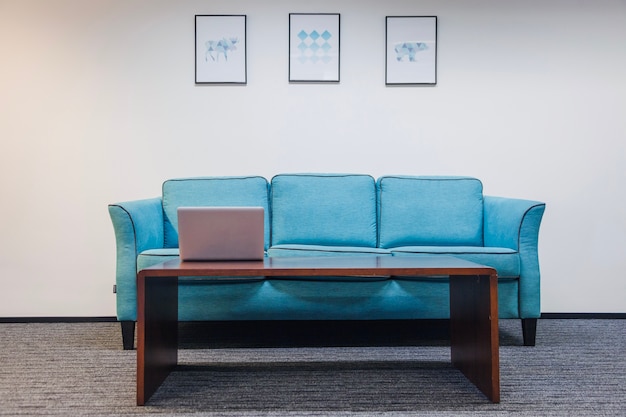 Photo table with laptop sofa standing in room