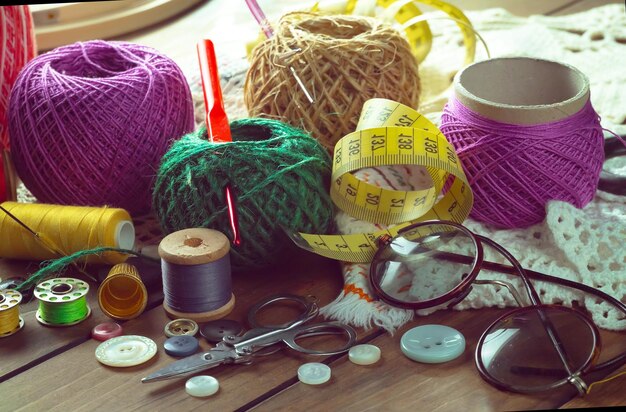 A table with a lot of items including a pair of glasses, a yellow measuring tape, a pair of scissors, a pair of glasses, a pair of glasses, a pair of glasses,