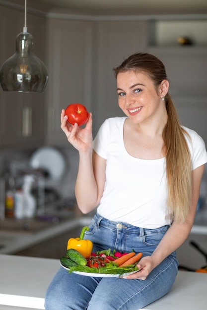 At the table with lots of vegetables woman is sitting