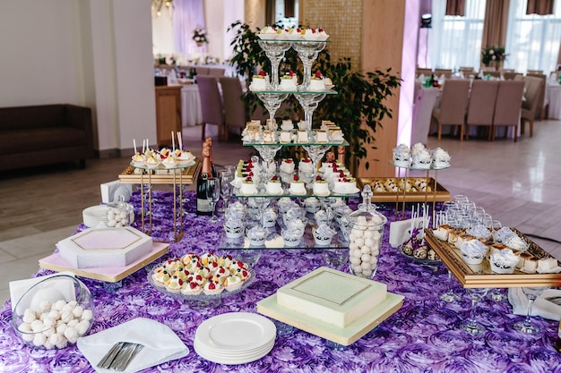 Table with muffins cakes sweets candy buffet dessert table for\
a party goodies for the wedding banquet area close up candy bar\
decorated delicious