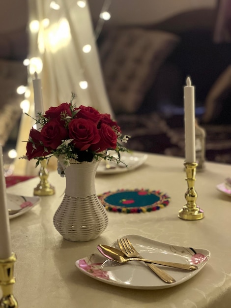 A table with a plate and a vase of roses on it