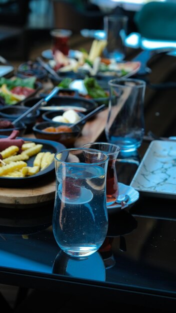 Photo a table with plates of food including pasta and water