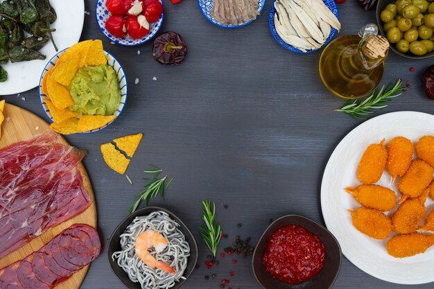 Table with spanish tapas - anchovies with peppers padron, jamon, croquetes, guacamole and olives