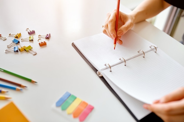 On a table with stationery, a woman makes a notepad . High quality photo