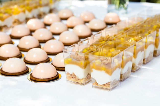 Table with sweets decorated with flowers and macaroon cakes and light desserts in cups