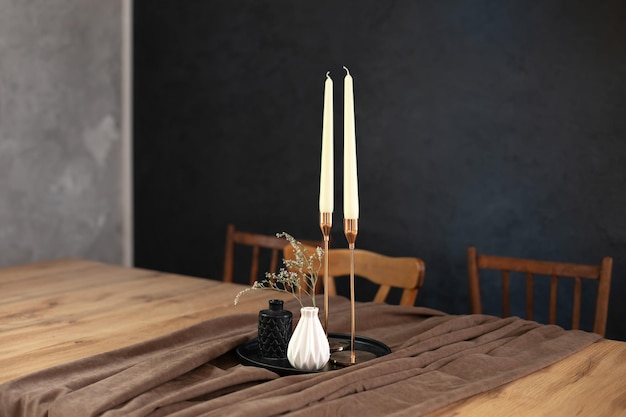 On table with tray are candles in candlesticks and a vase of flowers in room. Cozy home  decor