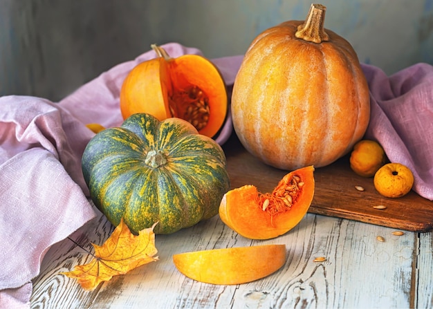 A table with a variety of pumpkins and a cutting board with a wooden cutting board