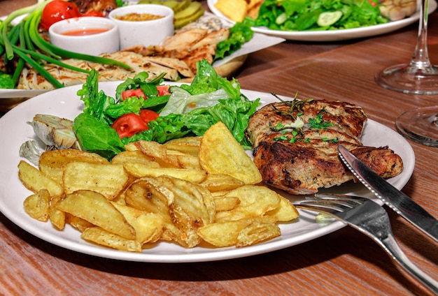 Foto tavolo con vari piatti di carne e verdure e patate fritte