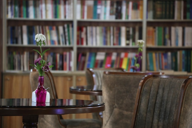 A table with a vase of flowers on it and a bookshelf in the background