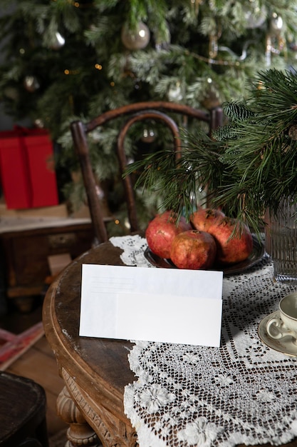 Photo table with white envelope and horizontal postcard flyer mockup in retro christmas decorations