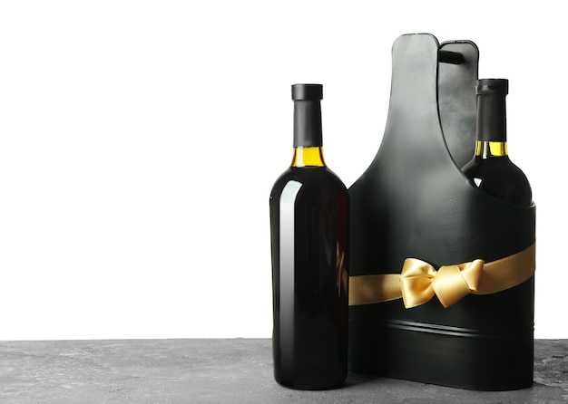 Table with wine bottles and gift box on white background