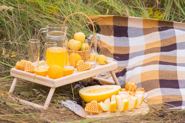 A table with yellow fruits and pastries at a picnic in summer