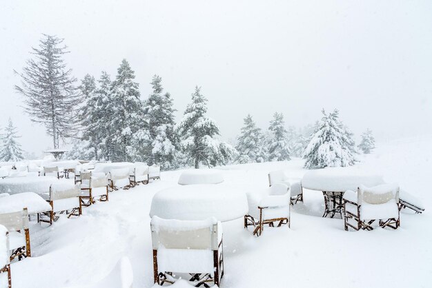 The tables and chairs of a restaurant are covered by heavy snow