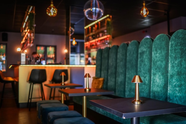 Photo tables with golden lamps next to a green velvet sofa in a nightclub photo