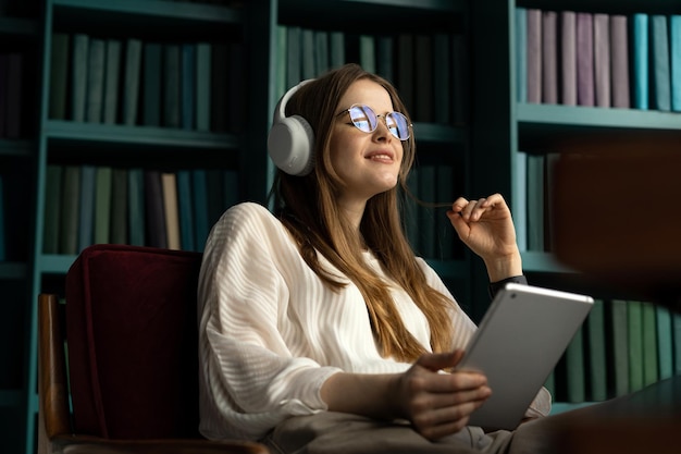 Tablet audioboek vrouw draadloze koptelefoon kantoor werkplek rapport plaats Een student met een bril in de bibliotheek