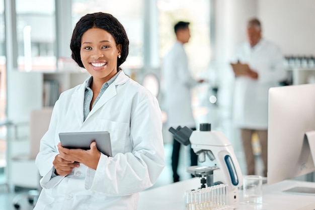 タブレットの黒人女性と研究室の病院や医学化学やイノベーションのための科学研究の科学者の肖像画診療所や研究室で笑顔を持つ医師の技術と医療従事者