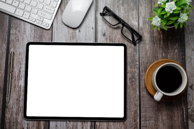 tablet blank white screen with coffee notebook eyeglasses calculator on wooden desk work