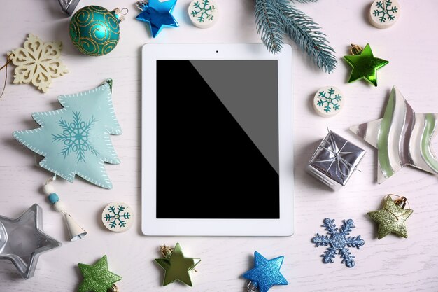 Tablet and Christmas decor on white surface wooden surface