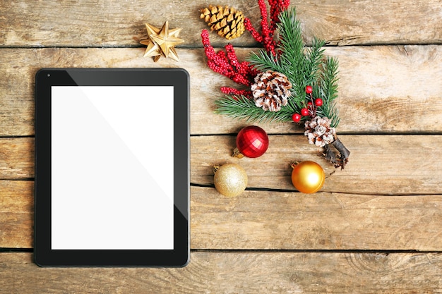 木製の背景にタブレットとクリスマスの装飾