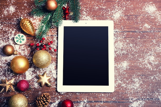 Tablet and Christmas decor on wooden background