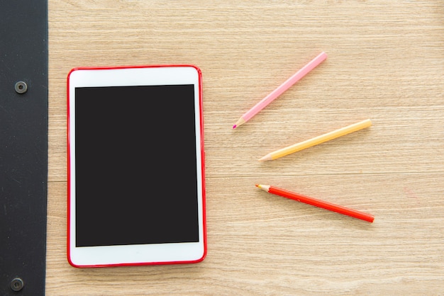 Tablet e matita colorata sul tavolo di legno.