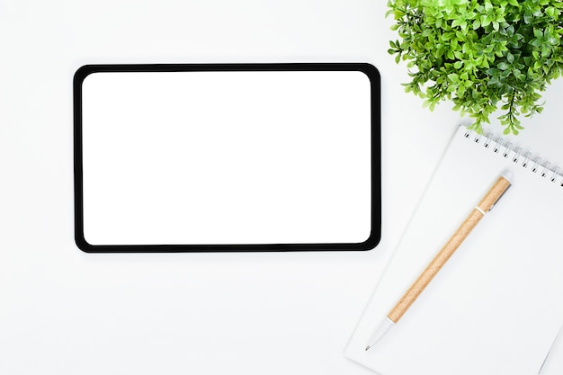 Tablet computer, pen with notepad and house plant on a light table