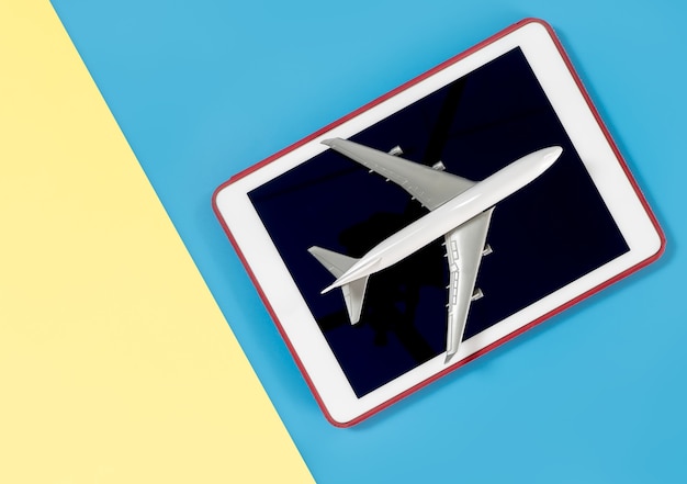 Tablet for copy space with plane for travel concept on blue yellow pink