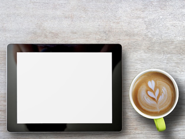 Tablet and cup of coffee on wood table background