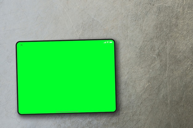 Tablet green screen on cement background. Top view. Chroma Key.