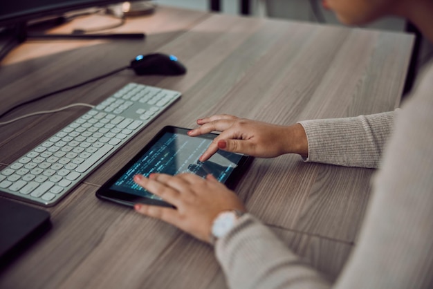 オフィスの机の上でコーディングまたはプログラミングを行うためのタブレットの手とプログラマ画面 情報技術の女性開発者と、職場でのソフトウェア開発のためのデジタル タッチスクリーンを持つ女性