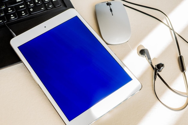 Tablet met blauw scherm naast een laptop op een bureau Technologie en bedrijfsconcept