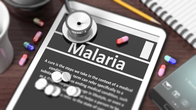 Tablet met Malaria op scherm stethoscoop pillen en objecten op houten bureaublad