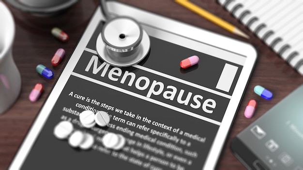 Tablet met menopauze op scherm stethoscoop pillen en objecten op houten bureaublad