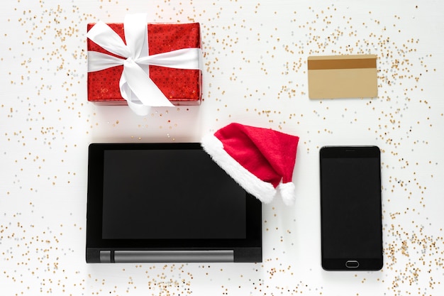 Tablet, mobiel, creditcard en geschenkdoos met gouden confetti