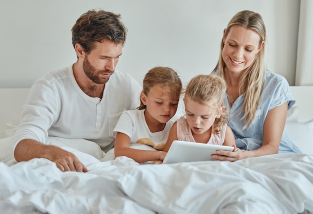 Tablet movie and family in bedroom streaming a lovely series on subscription online and relaxing on a lazy morning Mother father and children watching tv for bonding and entertainment on a weekend