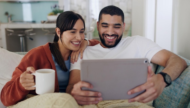 Tablet paar en glimlach op de bank in huis voor sociale media grappig nieuws en online meme Gelukkige man vrouw en ontspan met digitale technologie webabonnement en streaming film op netwerkverbinding