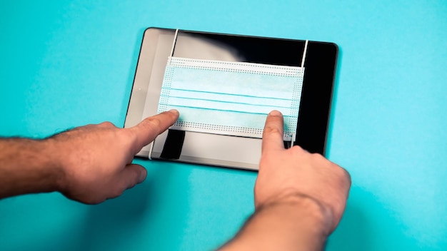 Tablet pc with face mask on blue background