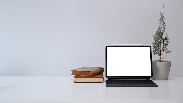 Tablet, plant and books on white table. Copy space for products display montage.