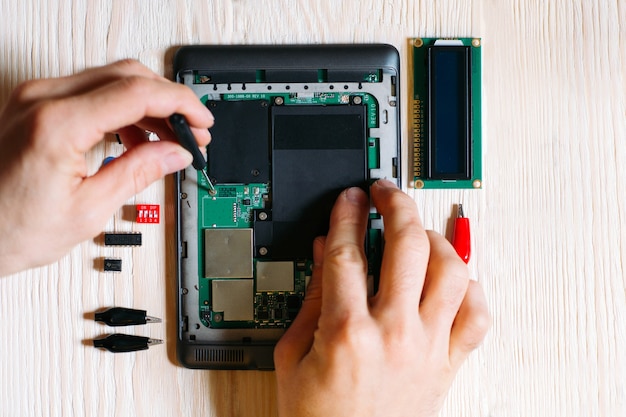 Tablet repair by male hands on wooden table