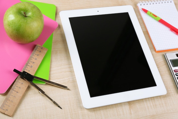 Tablet e materiale scolastico sul primo piano della tavola di legno