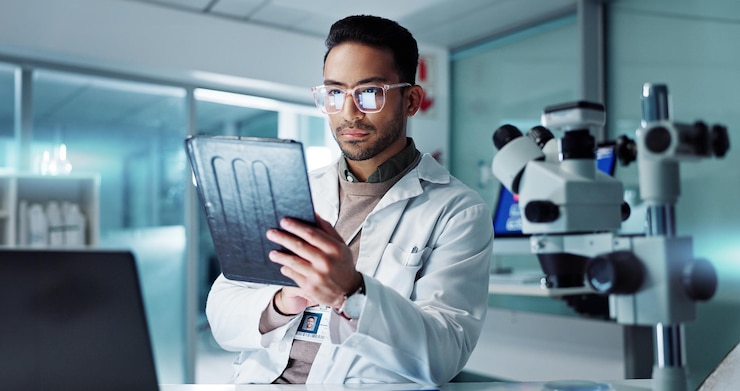 Photo tablet scientist and reading for analysis in laboratory healthcare and online pharmaceutical research asian expert computer and microscope for medicine and information on innovation cure at work