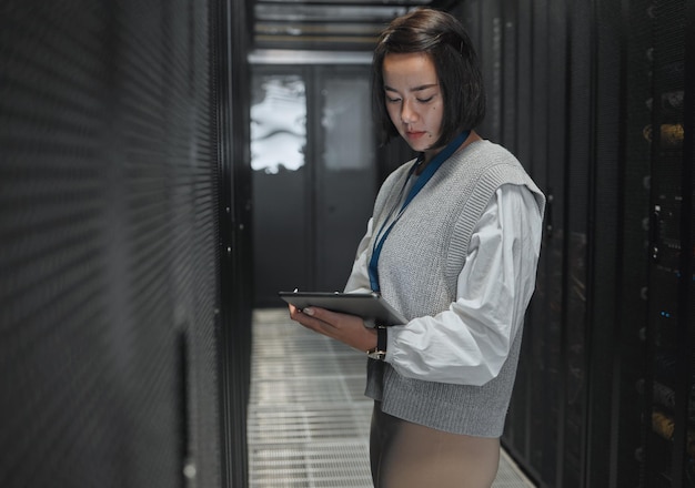 Foto sala server tablet e dashboard con un programmatore donna asiatica al lavoro su un computer mainframe database software e tecnologia dell'informazione con un programmatore femminile che lavora da solo su una rete informatica