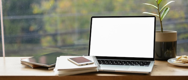 Tablet smartphone and laptop white screen mockup with accessories on portable cafe workspace