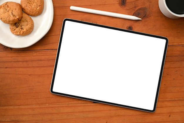 Tablet-touchpad leeg display met styluspen een bord koekjes en een kopje koffie op houten tafel