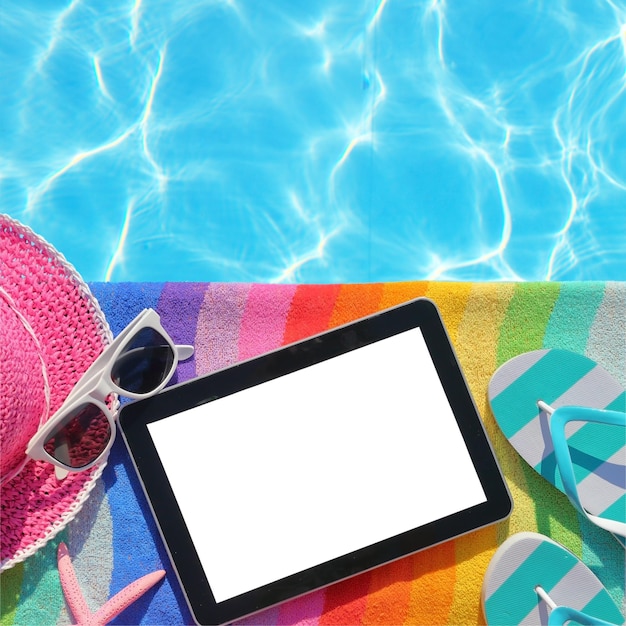 Foto tablet con schermo vuoto a bordo piscina con accessori da spiaggia
